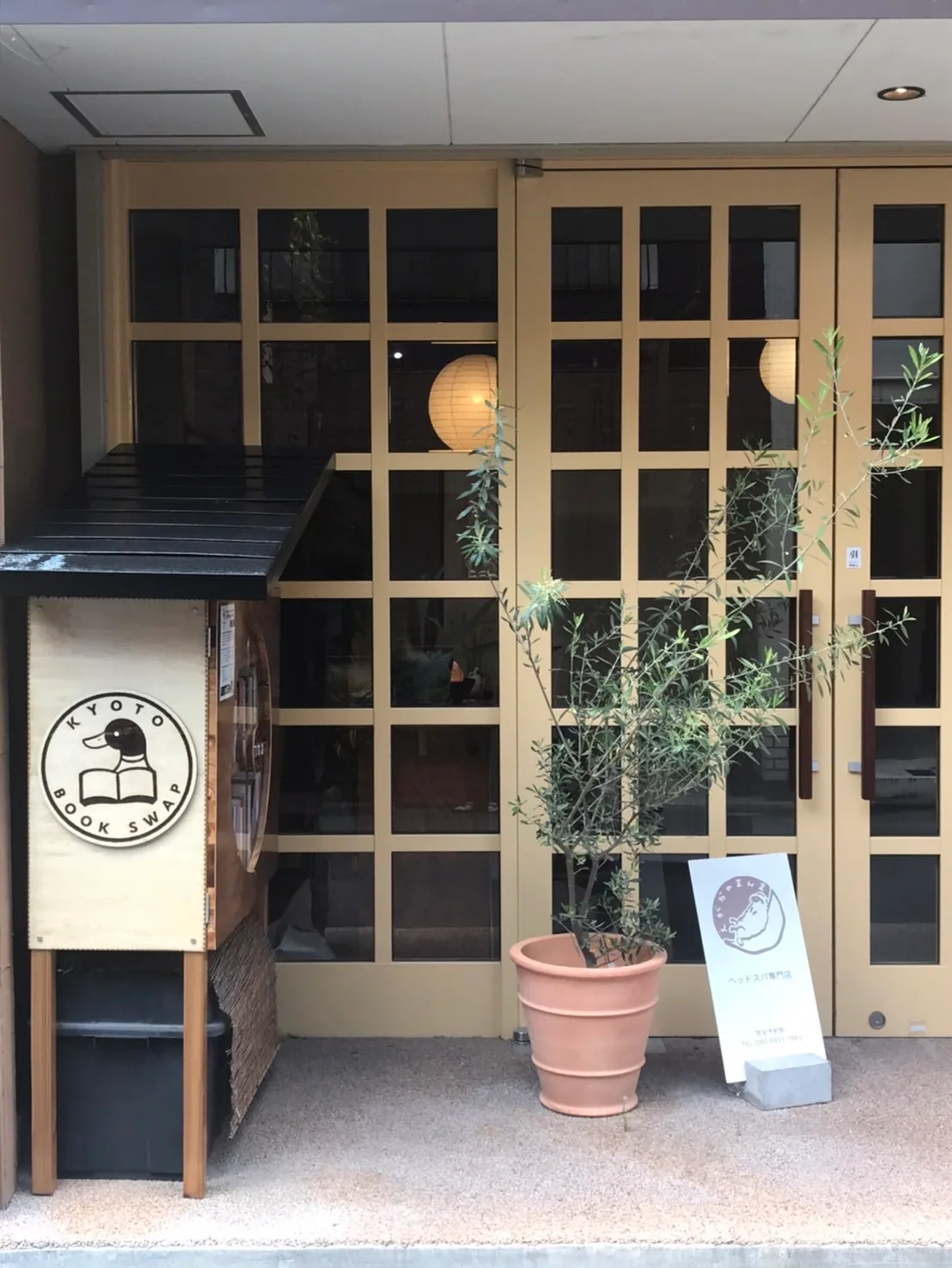 京都の建物の入口、書店の看板と鉢植えの木